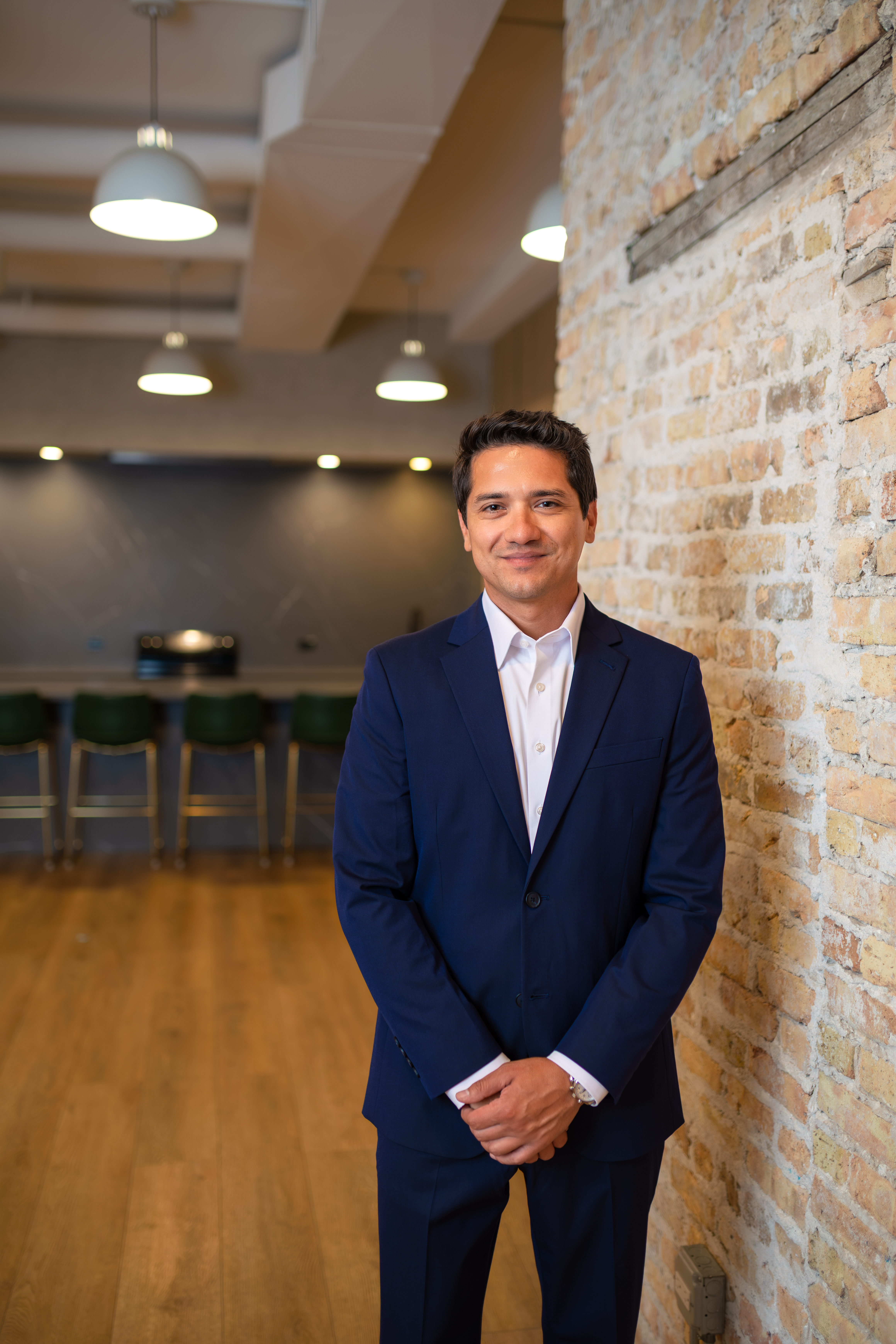 Andy Andrade, founder of Shore Properties Group, standing beside an exposed Chicago brick wall